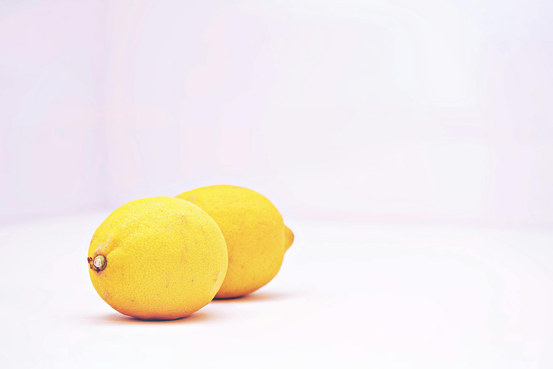 A minimalistic arrangement of vibrant lemons against a white background, representing the fresh approach to pleasure